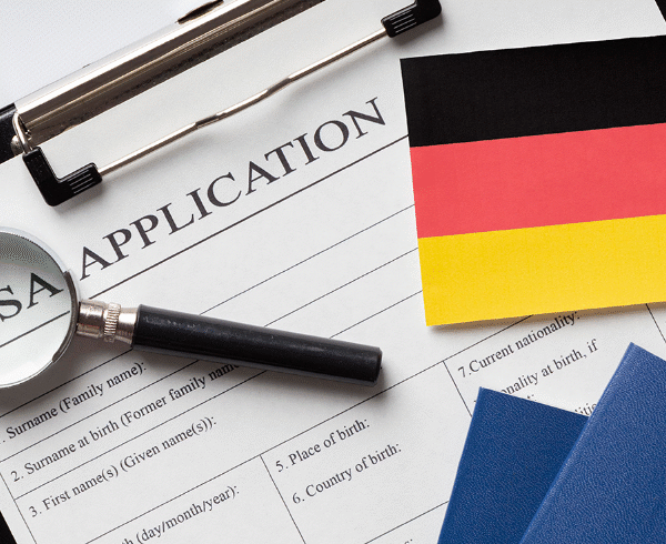German flag on visa application form with passports and magnifying glass, symbolizing student visa process and international study opportunities in Germany.