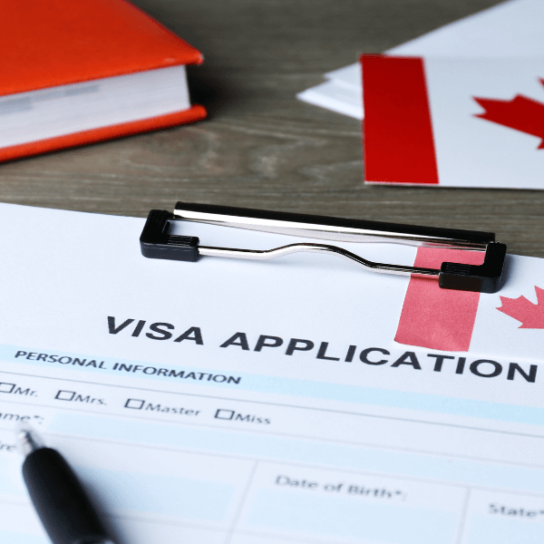Canadian flag on visa application form with pen and clipboard, representing student visa process and international study opportunities in Canada.