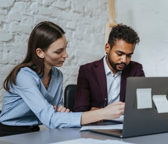 A professional consultation between a man and woman reviewing study abroad applications on a laptop with ASK Consultants guidance.