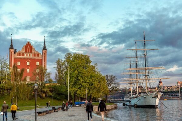 Waterfront view of Stockholm, Sweden, showing the historic red Admiralty House and the af Chapman sailing ship, perfect for students considering study abroad with ASK Consultants.